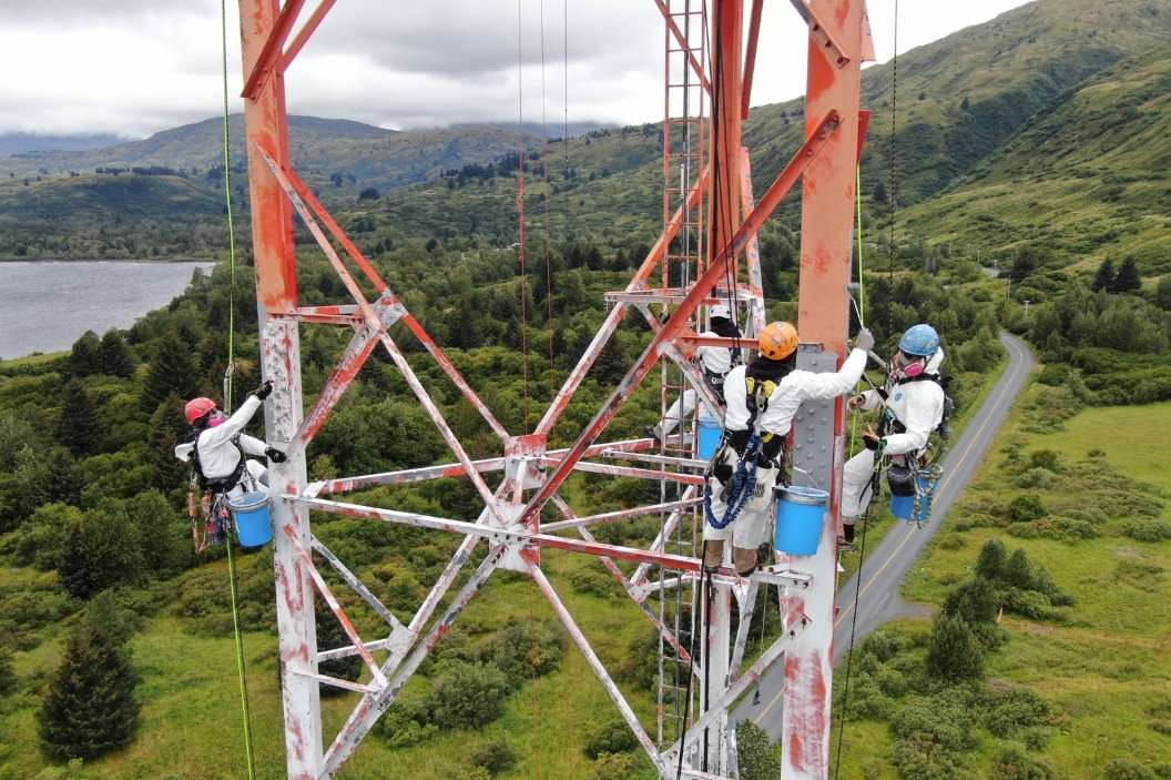 Painters working on a red and white lattice tower