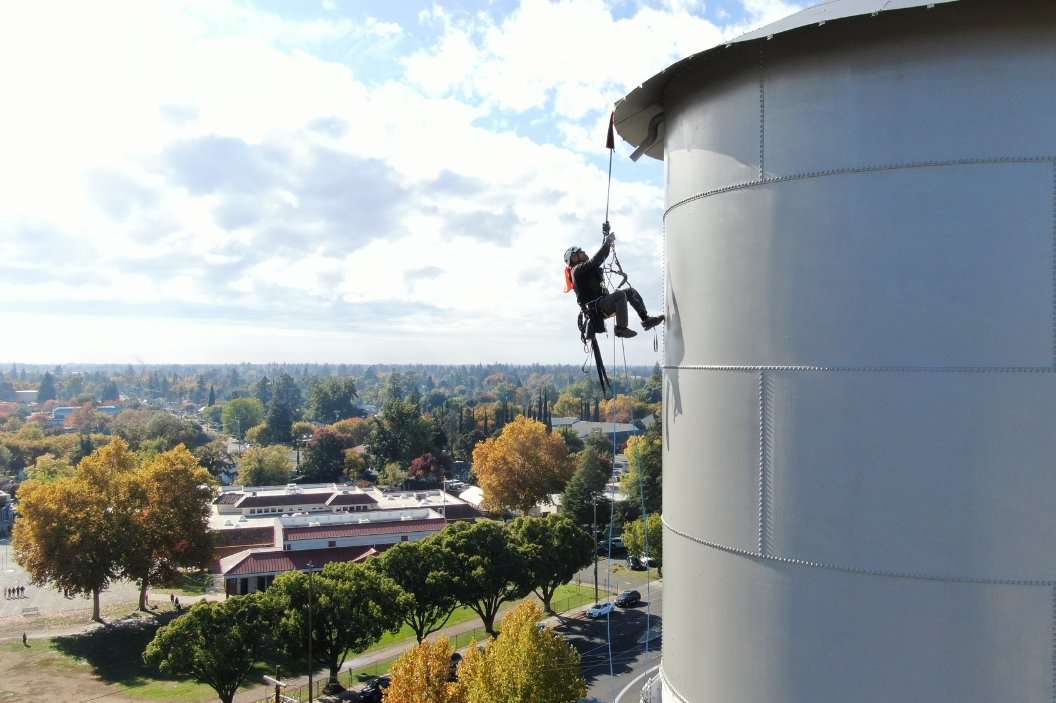 Painter abseiling down a large water tower