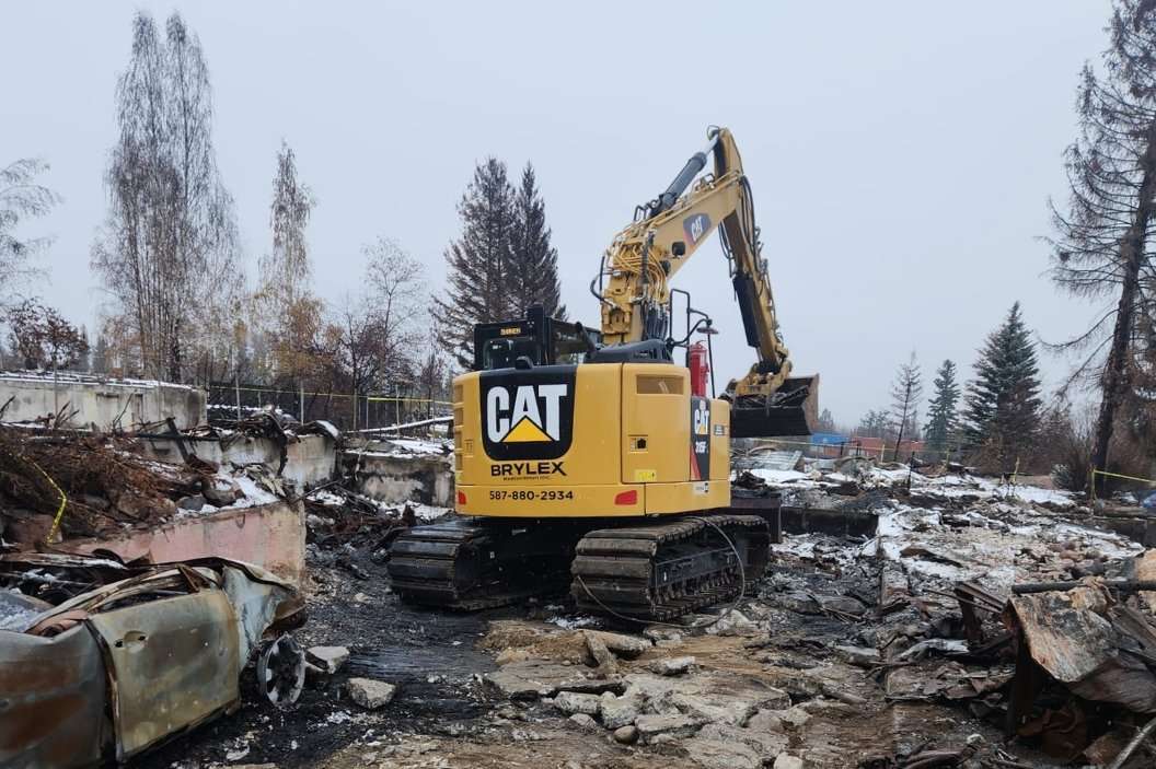 Excavator clearing fire damaged debris during a restoration job