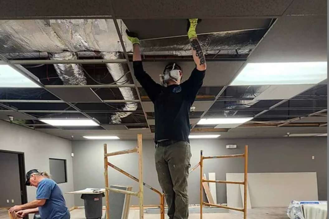 Worker on a lift installing ceiling services
