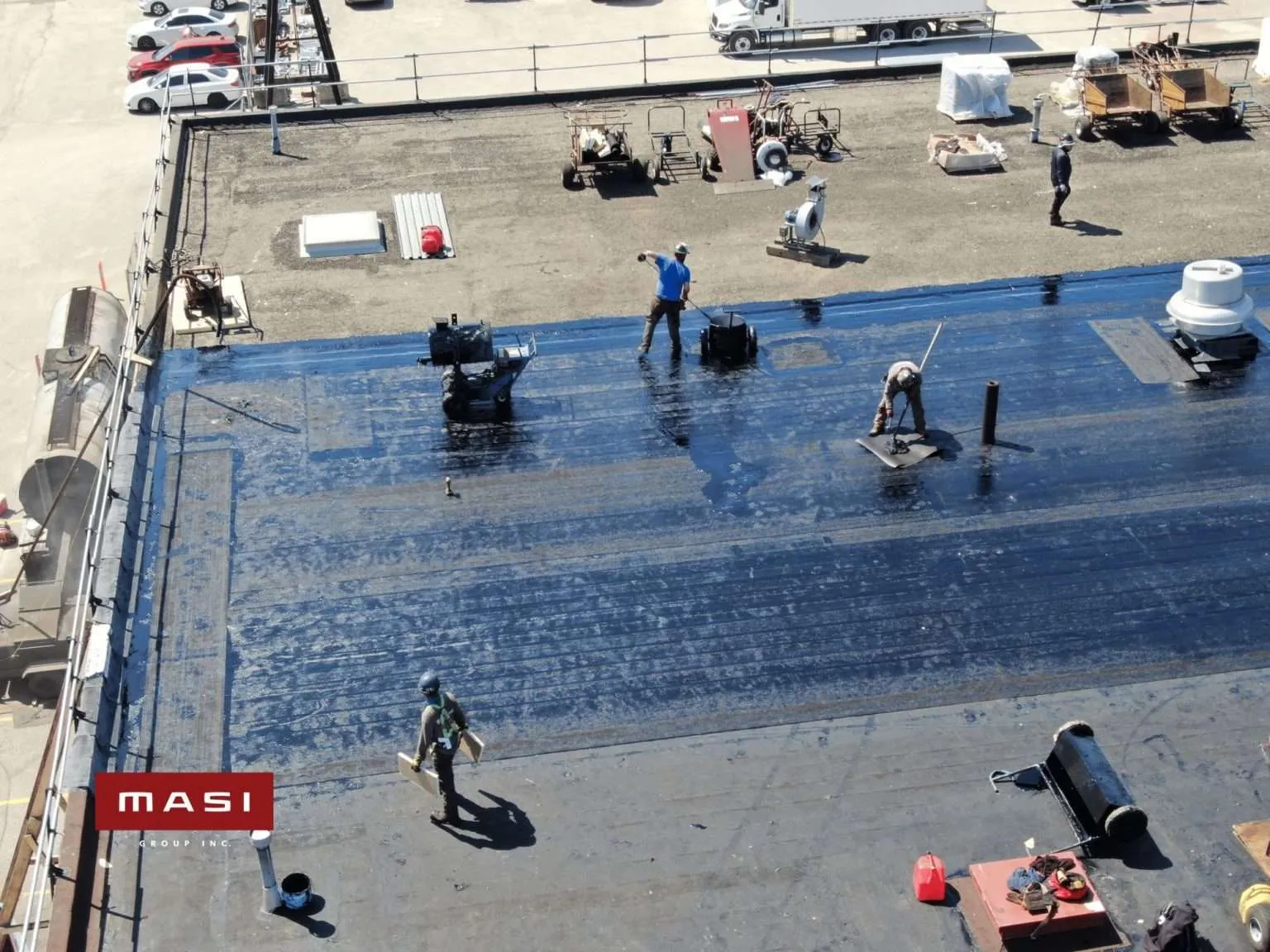 Crew installing blue roofing membrane on a flat roof