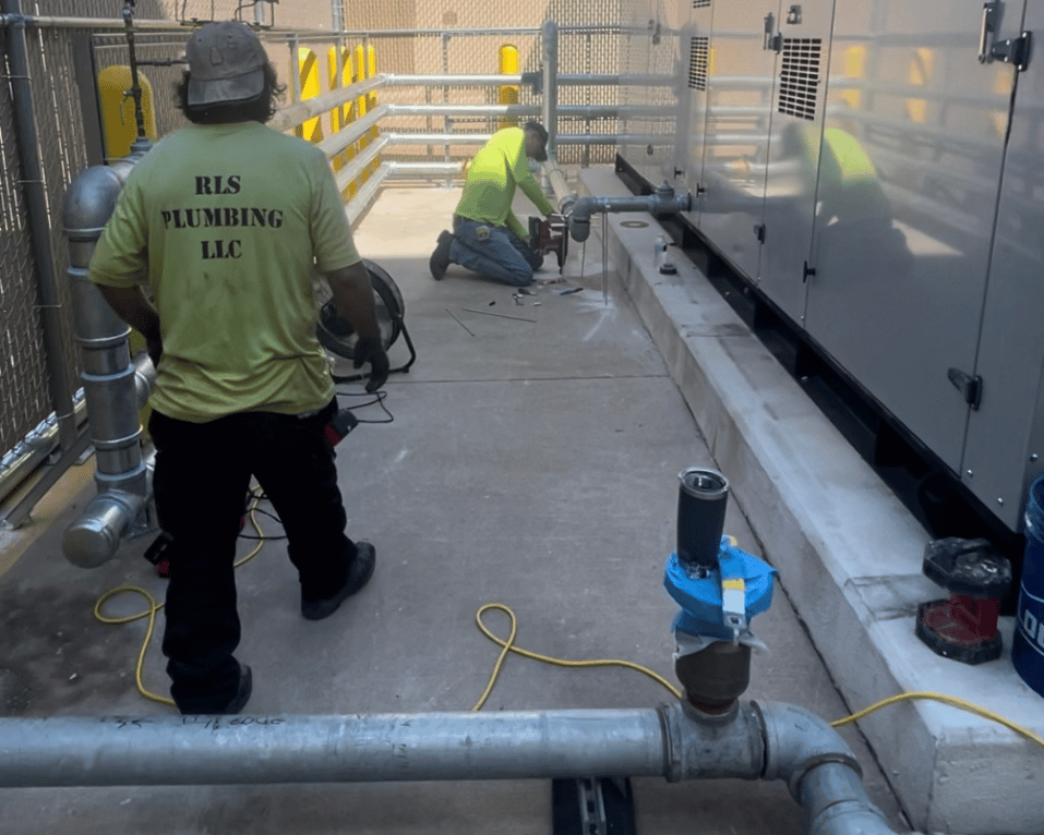 Plumber working on pipework below floor level