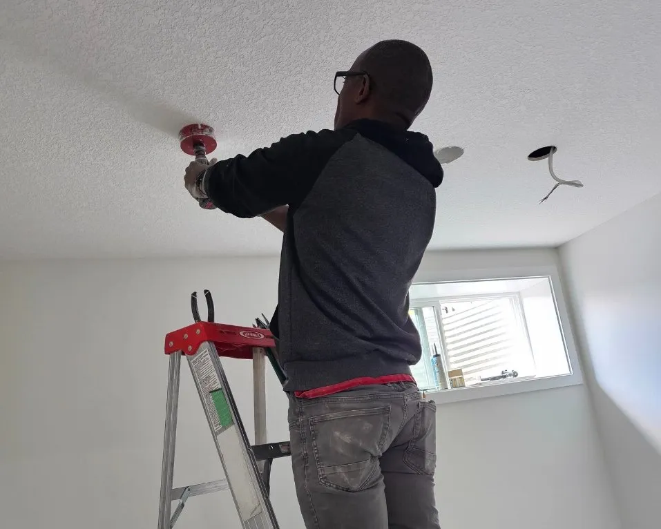 Decorator painting an interior wall from a ladder
