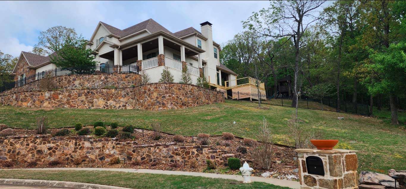 House under construction on a hillside with stone retaining wall