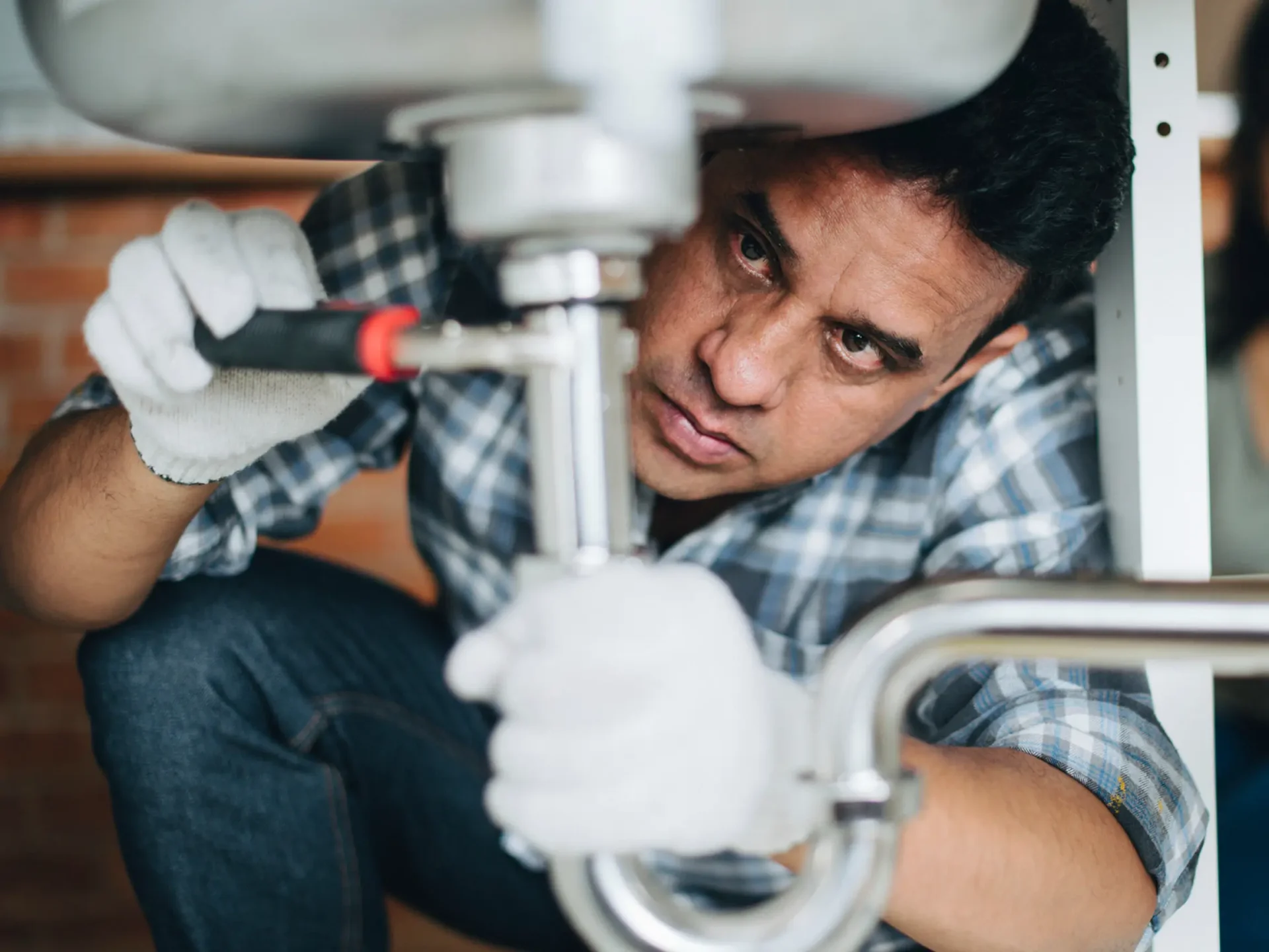 Plumber fitting pipework beneath a sink