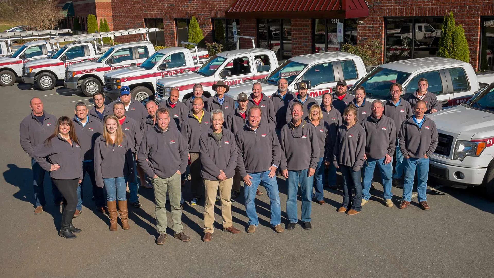 Roofing company team in front of their truck fleet