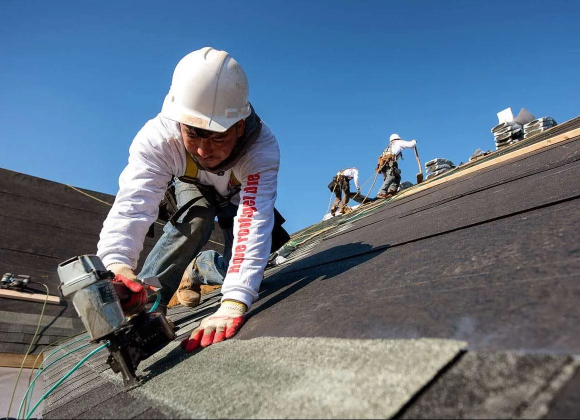 Roofer installing shingles on a sloped roof