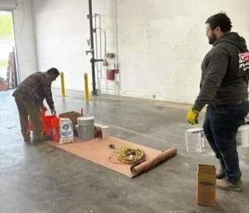 Worker coating a corridor floor with resin